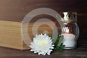 White memorial candle, chrysanthemum flower and book