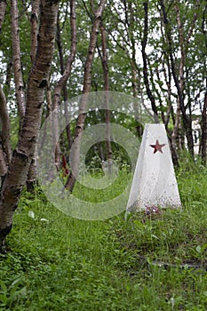 White memorial obelisk wed red star  on a green forest background photo