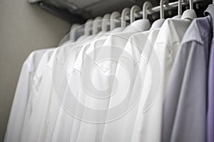 White men`s shirts on hangers in wardrobe