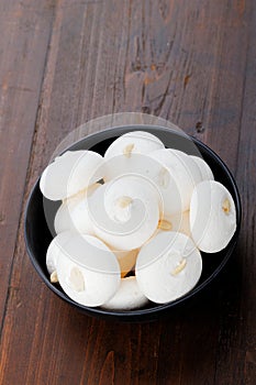White meringues on a black plate on a wooden background.