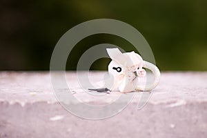 A white metal decorated wedding lock lies on a wooden parapet and next to it is the key. Blured greenery in the