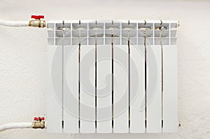 White metal heating radiator forming part of a central heating system with energy-efficient thermal insulation on the wall