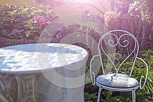 White metal iron chair and table outdoors. Retro styled furniture in magic green summer garden, symbols of Alice in Wonderland