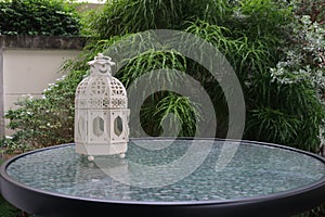 White metal lattern in retro design on mirror table in garden