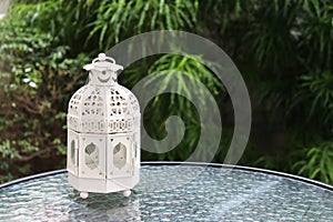 White metal lattern in retro design on mirror table in garden