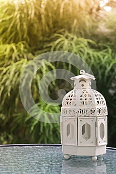 White metal lattern in retro design on mirror table in garden