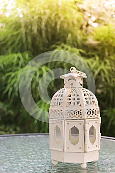 White metal lattern in retro design on mirror table in garden