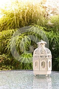 White metal lattern in retro design on mirror table in garden