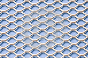 White metal mesh with small cells on a blue background. Close-up. Macro. Industrial background
