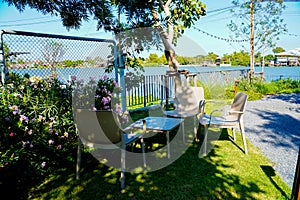 A white Metal outdoor garden furniture, table and chair set in the home small garden under the tree shade with the afternoon light