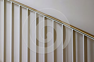 White metal pickets and brass staircase railing against white wall