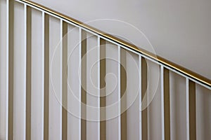 White metal pickets and brass staircase railing against white wall photo