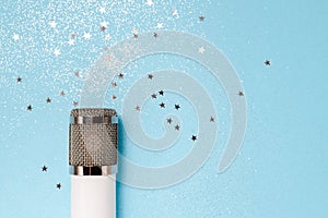 White metalic microphone with stars on classic blue background. Top horizontal view copyspace. Interview and podcast concept