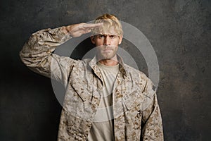 White military man wearing uniform saluting and looking at camera