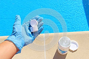 White mini chlorine tablet in the hand of a service worker for disinfection of swimming pools. photo