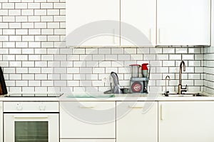 White minimalistic kitchen interior and design. Tile wall background. Household appliances - blender, vacuum machine