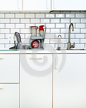White minimalistic kitchen interior and design. Tile wall background. Household appliances - blender, vacuum machine