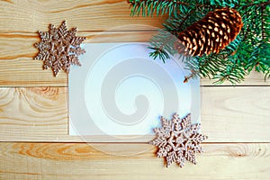 White mockup blank, Christmas tree branches and Christmas decorative snowflakes on wooden background.