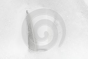 White mockup of a tube of cream in water with foam on a white background. Concept of washing gels, moisturizer, cosmetics for