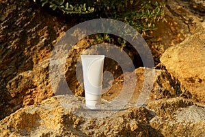 White mockup of a tube of suntan or sun protection cream on yellow limestone by the sea. The concept of natural cosmetics