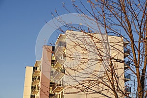 White modern apartments building facade in sunlight on a sunny day with clear blue sky. Vana - Kuuli street. Tree with
