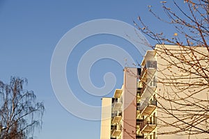 White modern apartments building facade in sunlight on a sunny day with clear blue sky. Vana - Kuuli street. Tree with