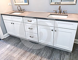 White modern bathroom cabinets with quartz countertop, two sinks and faucets with stone floor