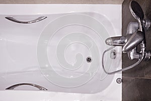 White modern bathtub with clean surface, handrails and tap faucet, clo