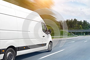 White modern delivery small shipment cargo courier van moving fast on motorway road to city urban suburb. Busines distribution and