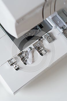 White modern ewing machine and its components close up. Sewing needle plate and replacement parts