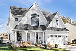 A white modern farmhouse with a black roof.