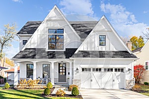 A white modern farmhouse with a black roof.