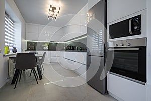 White modern kitchen with granite counter top and marble floor