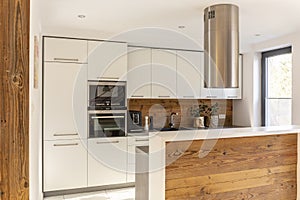 White modern kitchen interior with silver cooker hood above wood