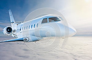 White modern luxury private jet flies in the air above the clouds