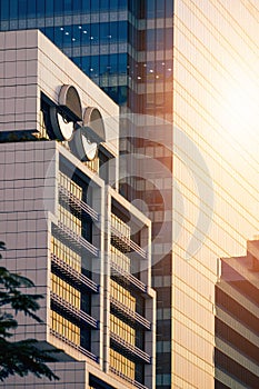 white modern office building with sunlight on glass wall surface of skyscraper in the city at evening time