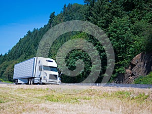 White modern semi truck reefer trailer on green summer highway