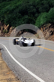 White modern sport car is driving on empty countryside asphalt road at sunset.