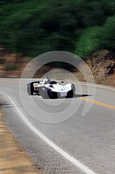 White modern sport car is driving on empty countryside asphalt road at sunset.