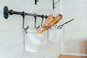 White modern stylish metal buckets with wooden shovels hanging on the kitchen wall. Cozy interior in a country house