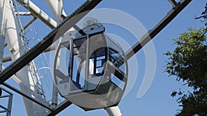 The white modern tech cabin of the ferris wheel rises up against the blue summer sky