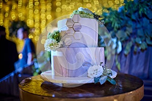 White modern wedding cake over wood table with amber lights