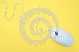 White modern wired computer mouse on yellow background