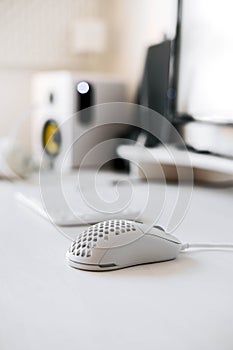 White modern wired gaming mouse in a white comfortable gamer workspace. Close-up of a special device