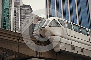 White monorail train against blue sky and modern skyscraper in Kuala Lumpur