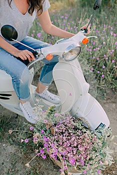 White moped with a girl and a basket of flowers