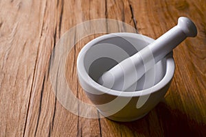 White mortar and pestle with pepper and spices mix on rustic wooden table.