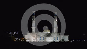 White mosque glowing at night in the middle east during call to prayer during ramadan.