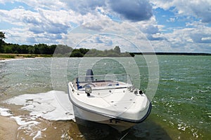 White motor boat motorboat stands near the shore of the lake
