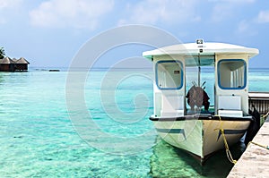 White motor boat tied at the pier against the clear water of the Indian Ocean